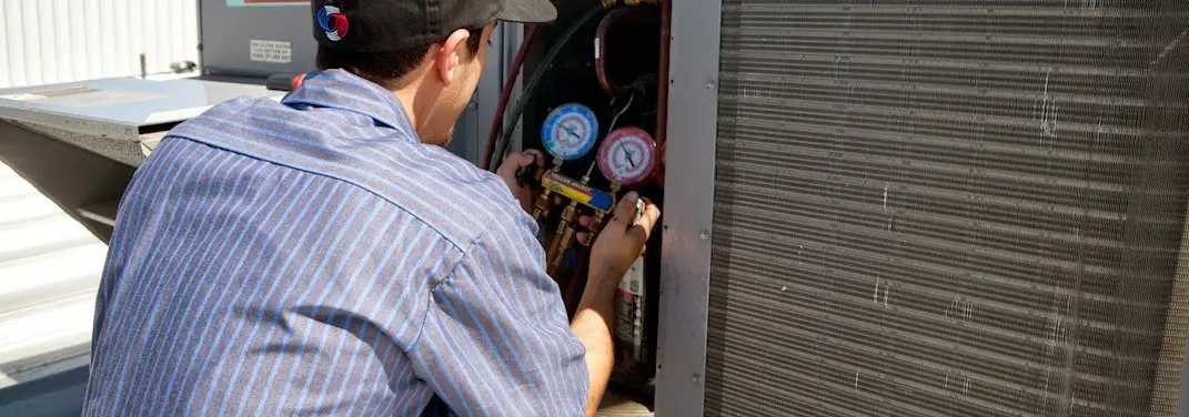 HVAC technician servicing a condenser unit in Cherokee